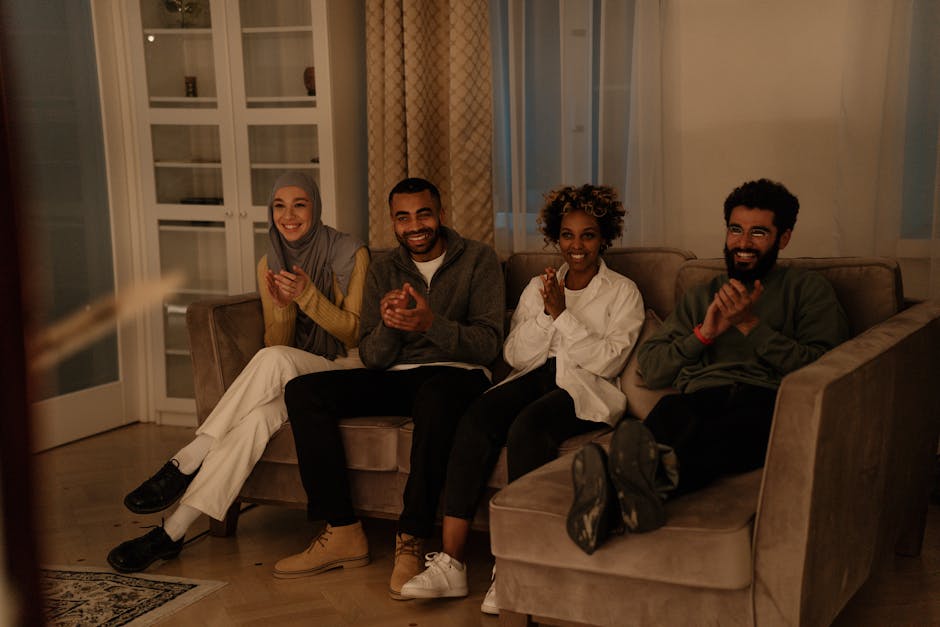 A diverse group of smiling people in comfortable clothing sitting together in a bright, modern room.