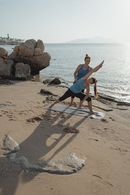 Woman performing a graceful yoga pose outdoors near calm water at sunrise
